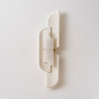 An unlit Clérachic wall lamp on a pale wall, the veined alabaster showing white and clouded between the beige panels.