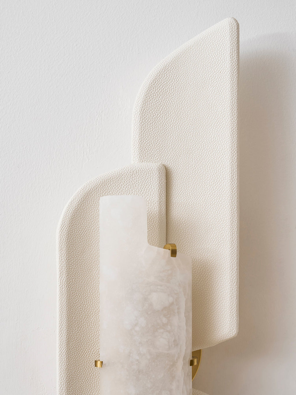 Close view of the beige pebbled panels and the alabaster slab held by small brass clips on this Clérachic wall lamp.
