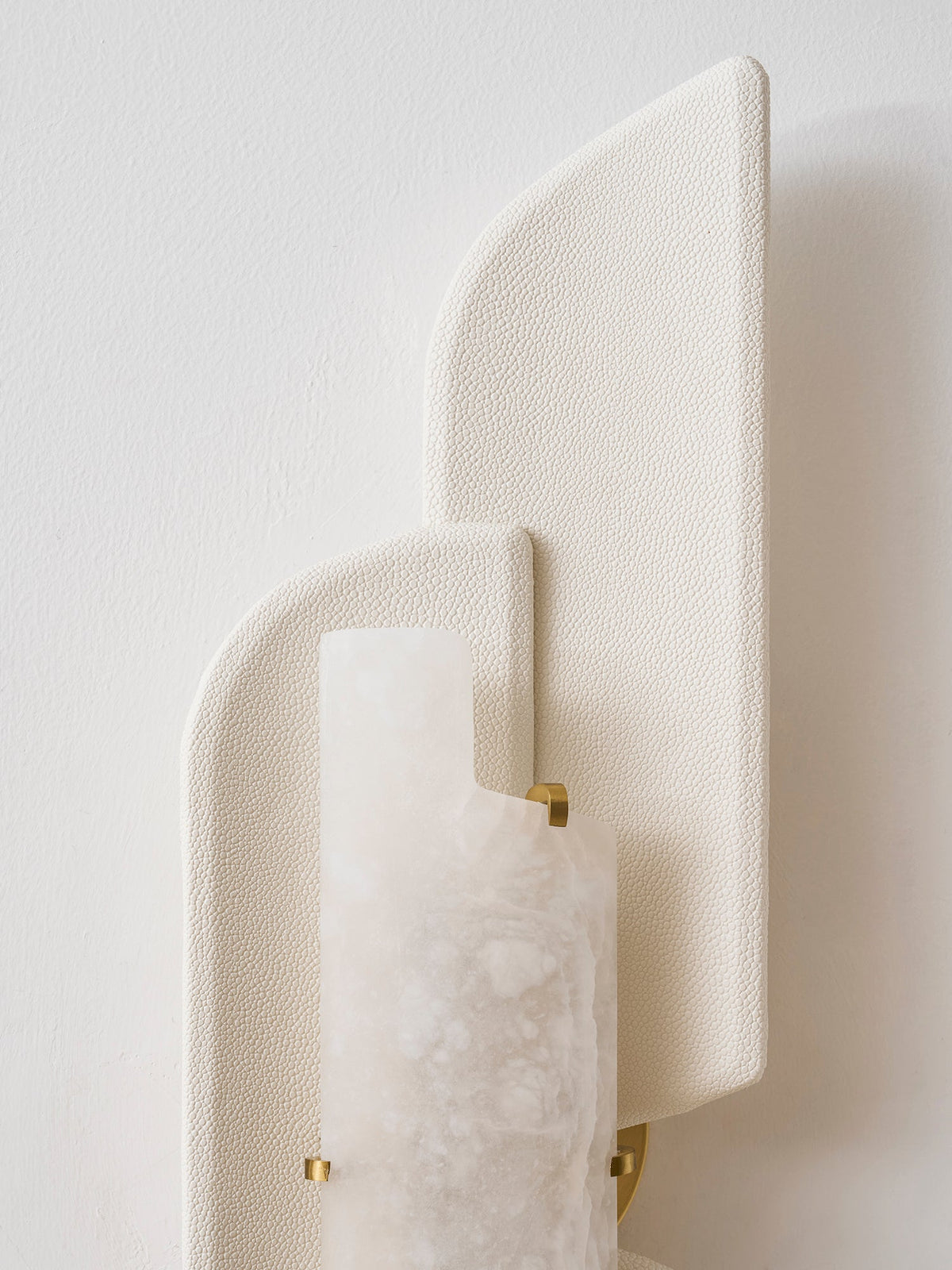 Close view of the beige pebbled panels and the alabaster slab held by small brass clips on this Clérachic wall lamp.