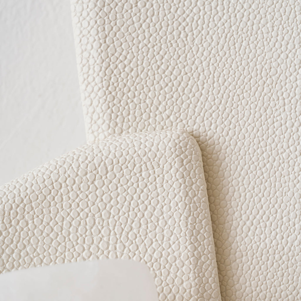 Close view of the pebbled, leather-like texture on the beige panels of this Clérachic wall lamp.