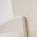 Close view of the pebbled, leather-like texture on the beige panels of this Clérachic wall lamp.