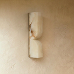 Clérachic hourglass-form alabaster wall light unlit, showing natural brown veining on a slim gold backplate.