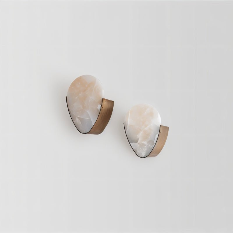 Clérachic pair of alabaster wall sconces with brushed brass backplates, each holding a soft peach-veined stone shield.