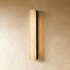Clérachic slim rectangular alabaster wall light in a black metal frame, softly glowing on a warm limewash wall in the studio.