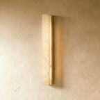 Clérachic slim alabaster bar wall light in a brushed gold frame, glowing gently against a warm limewash wall in the studio.