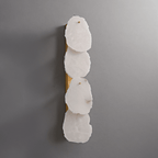 Clérachic four-light wall lamp unlit, four pale alabaster panels on a long brass backplate against grey.