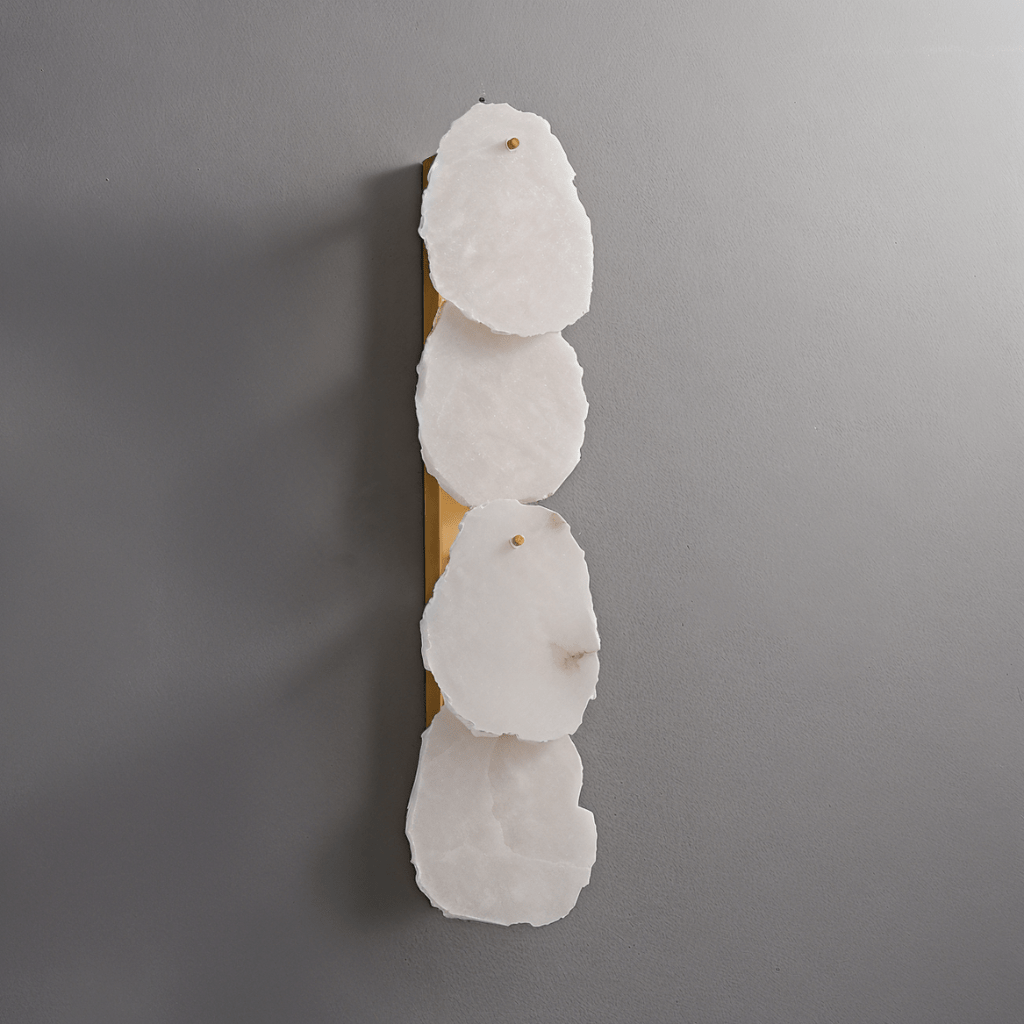 Clérachic four-light wall lamp unlit, four pale alabaster panels on a long brass backplate against grey.