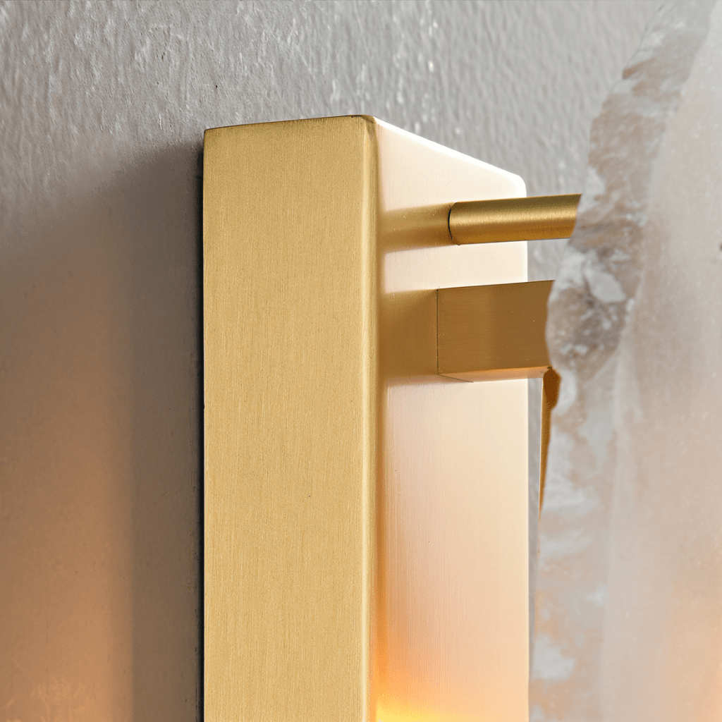 Side view of a Clérachic wall lamp showing the brushed brass backplate, rod and the edge of an alabaster panel.