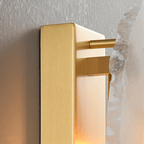 Side view of a Clérachic wall lamp showing the brushed brass backplate, rod and the edge of an alabaster panel.