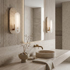 A Clérachic wall light glows above a stone basin in a bathroom with fluted wood panelling and a large mirror that shows a second light.