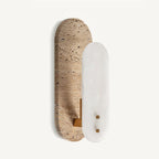Side-angled view of this Clérachic wall light, the white alabaster oval standing out from the taller travertine plate on a brass bracket.