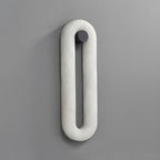 Clérachic Alabaster Wall Sconce unlit on a grey wall, one continuous oval loop of white stone on a small dark fixing.