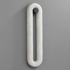 The taller Clérachic Alabaster Wall Sconce shown unlit, its slim white stone loop running down a plain grey wall.