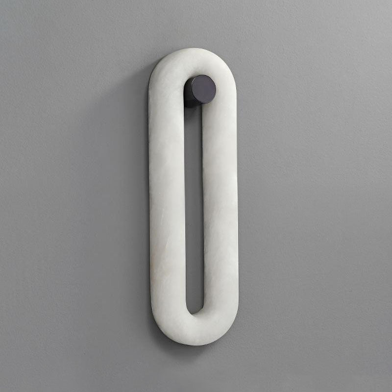 Clérachic Alabaster Wall Sconce seen straight on and switched off, the stone loop and its dark round wall fixing.
