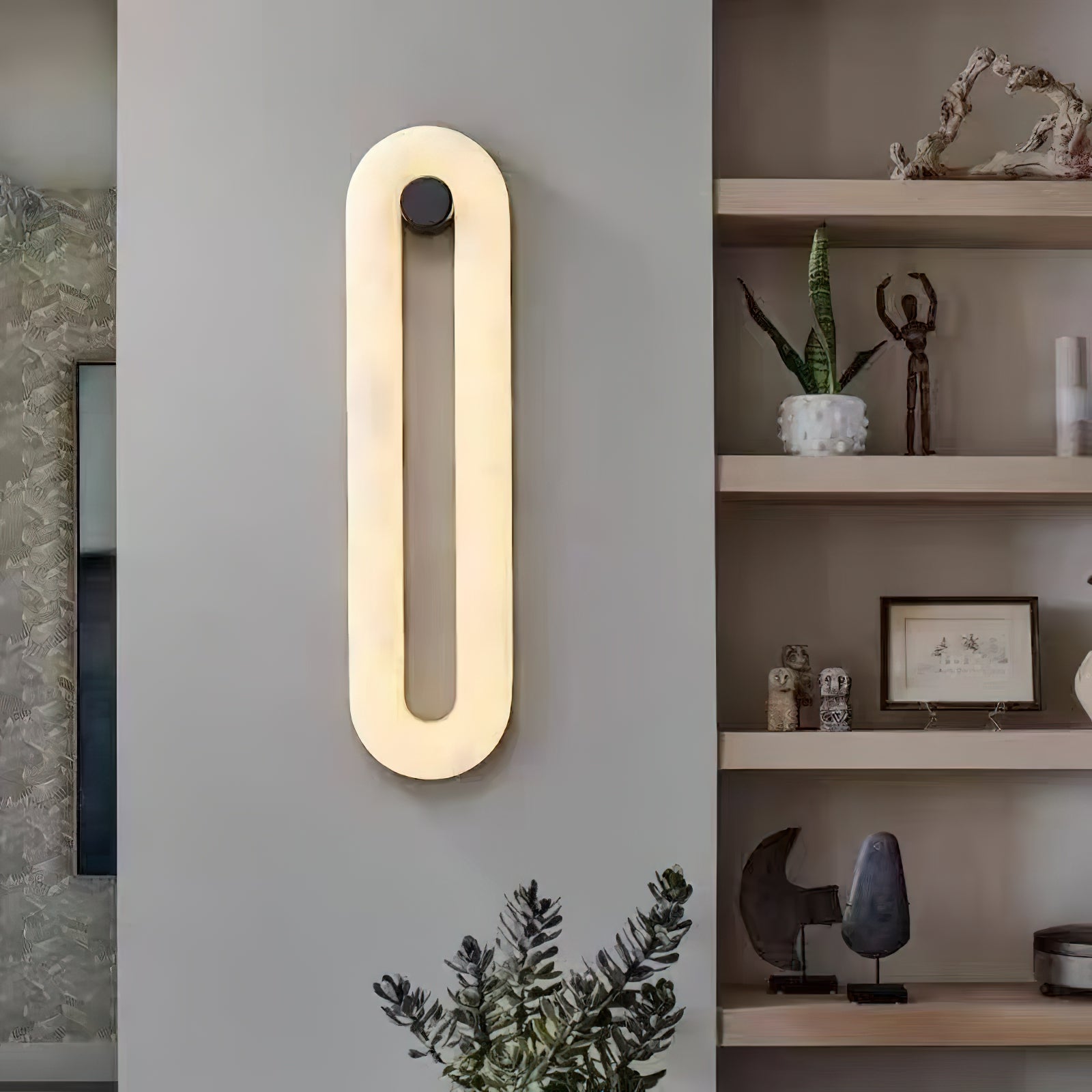 Clérachic Alabaster Wall Sconce lit beside open shelving, its warm oval of light set against a cool grey wall.