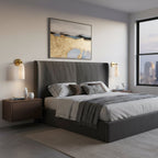 A pair of Clérachic alabaster wall lights beside a dark upholstered bed, with a city skyline visible through the window.