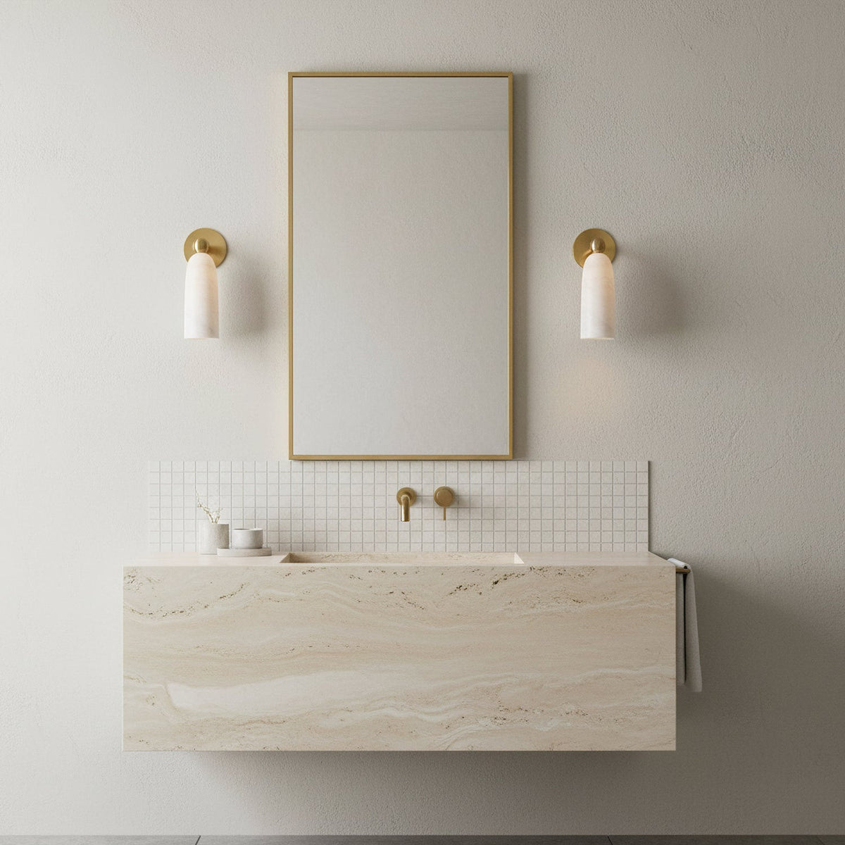 Brass-armed Clérachic sconces with white alabaster shades flanking a narrow gold-framed mirror over a stone vanity.