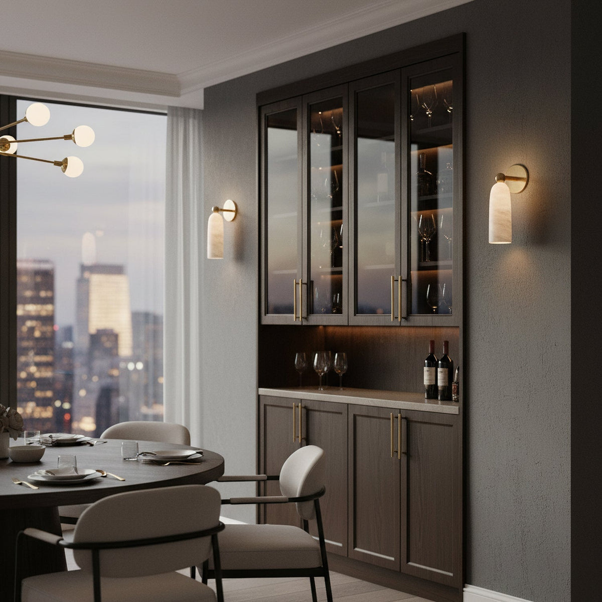 A Clérachic alabaster wall light on a dark dining-room wall, next to a glazed wine cabinet and a round table.