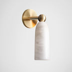 Brass backplate and arm with a rounded alabaster shade on this Clérachic wall light, shown in profile on a light grey backdrop.