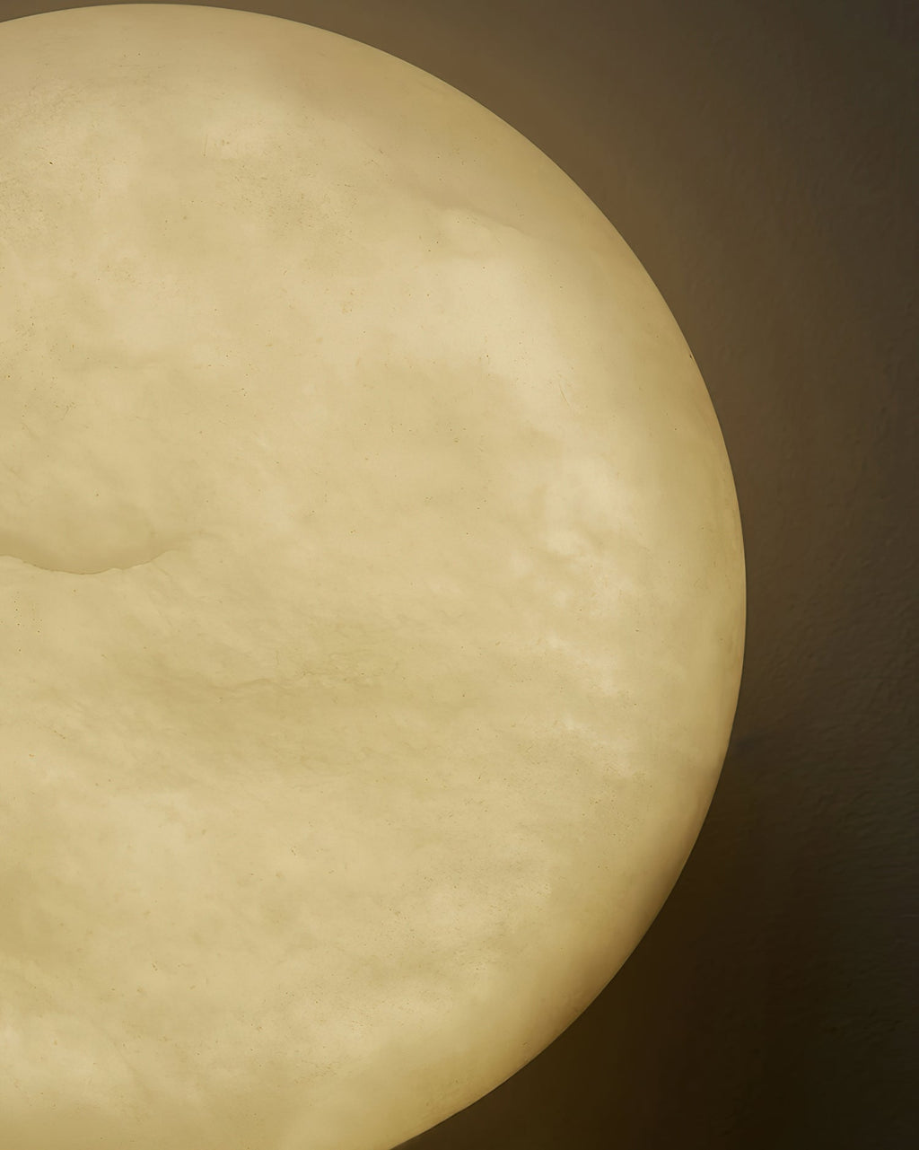 Macro of the Clérachic Alabaster Wall Sconce against a dark wall, the stone glowing amber from edge to edge.