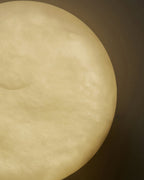 Macro of the Clérachic Alabaster Wall Sconce against a dark wall, the stone glowing amber from edge to edge.