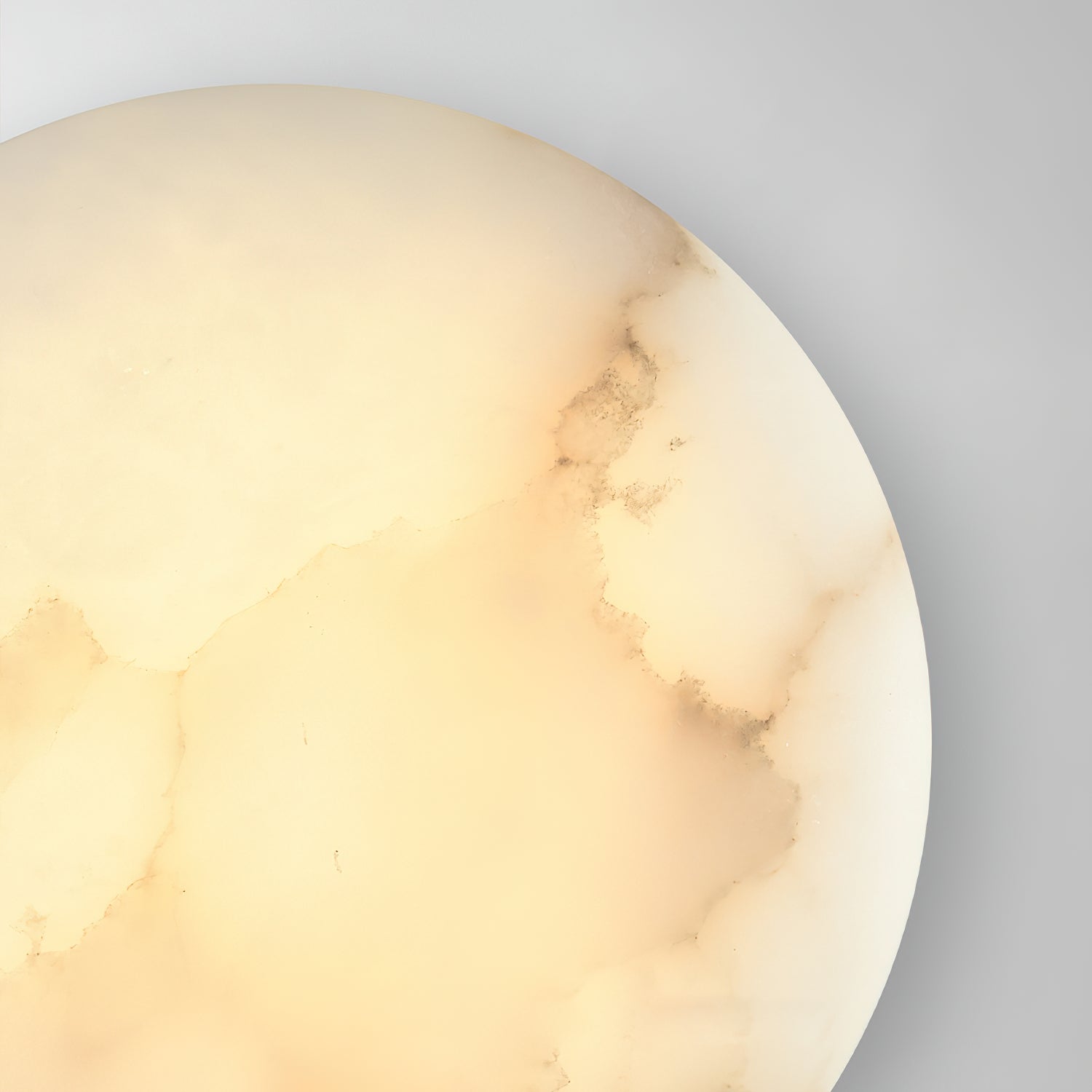 Close crop of the Clérachic Alabaster Wall Sconce, warm light picking out the grey veining near the rim.