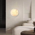 Clérachic Alabaster Wall Sconce lighting a textured wall by a dark doorway in a calm, low-furniture living room.