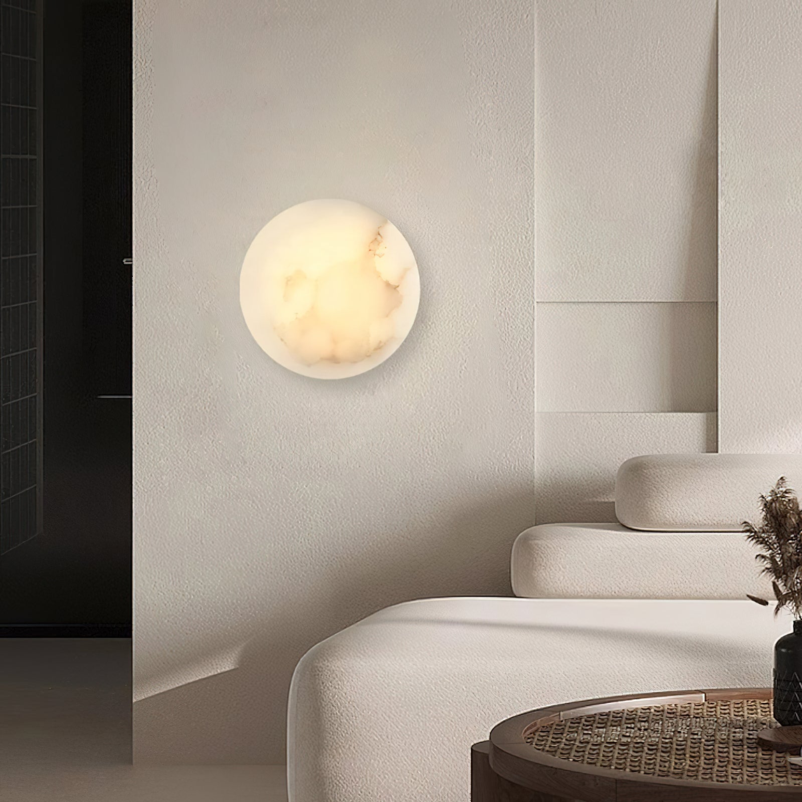 Clérachic Alabaster Wall Sconce lighting a textured wall by a dark doorway in a calm, low-furniture living room.