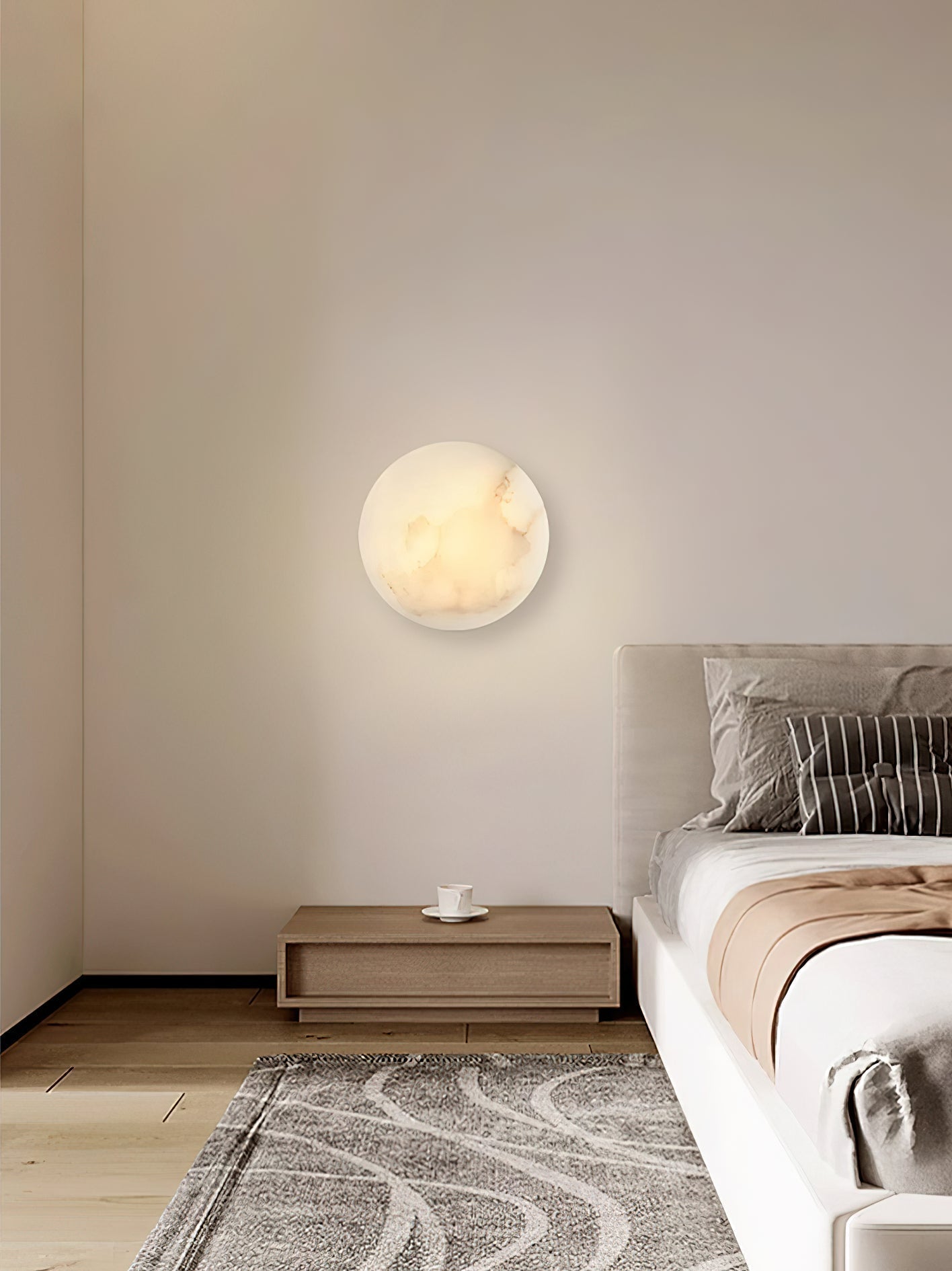 Clérachic Alabaster Wall Sconce glowing above a wooden nightstand in a quiet bedroom, next to a low bed.