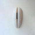 Full view of the Clérachic alabaster wall sconce switched off, the veined stone reading as one soft form against a plain painted wall.