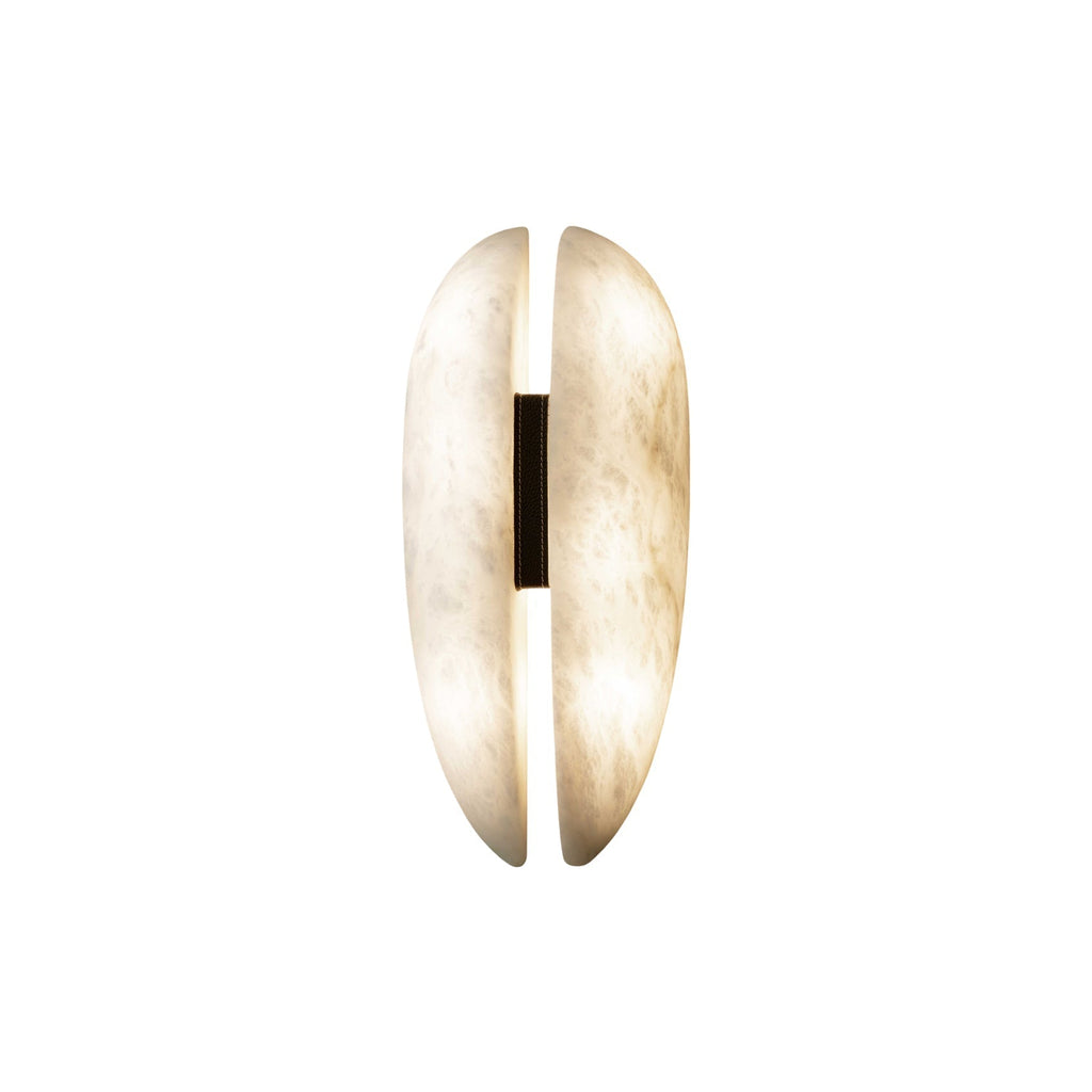 Studio shot of the Clérachic alabaster sconce lit, warm white light escaping the vertical slot and glowing through the translucent stone.