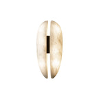 Studio shot of the Clérachic alabaster sconce lit, warm white light escaping the vertical slot and glowing through the translucent stone.