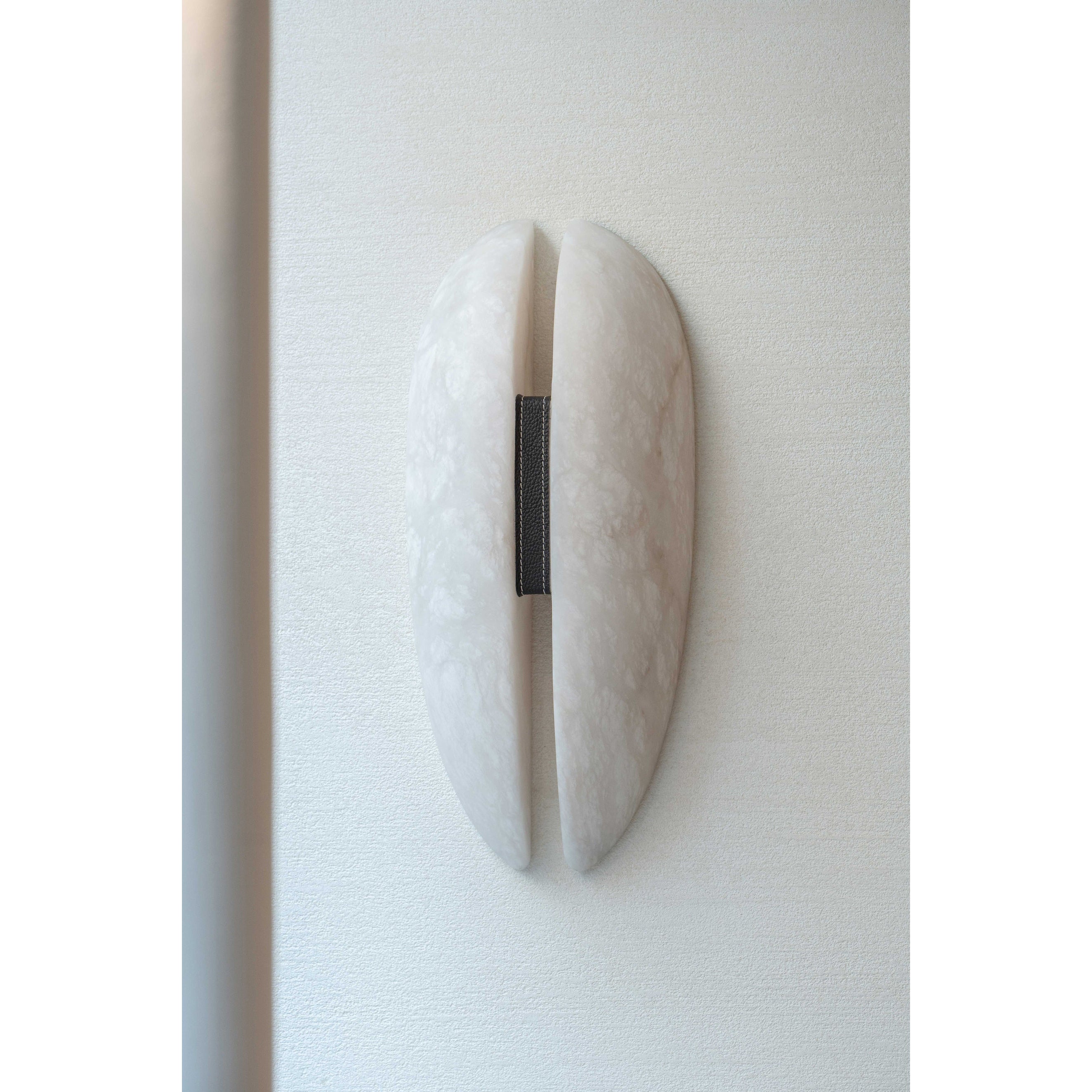 Clérachic alabaster sconce unlit beside a doorway, sitting flat to the wall with no cord or hardware in sight.