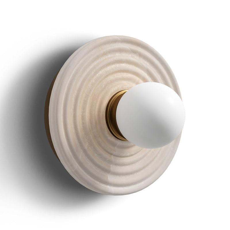 Side-angled view of the Clérachic alabaster sconce in gold, showing how shallow the ribbed disc keeps the fitting against the wall.