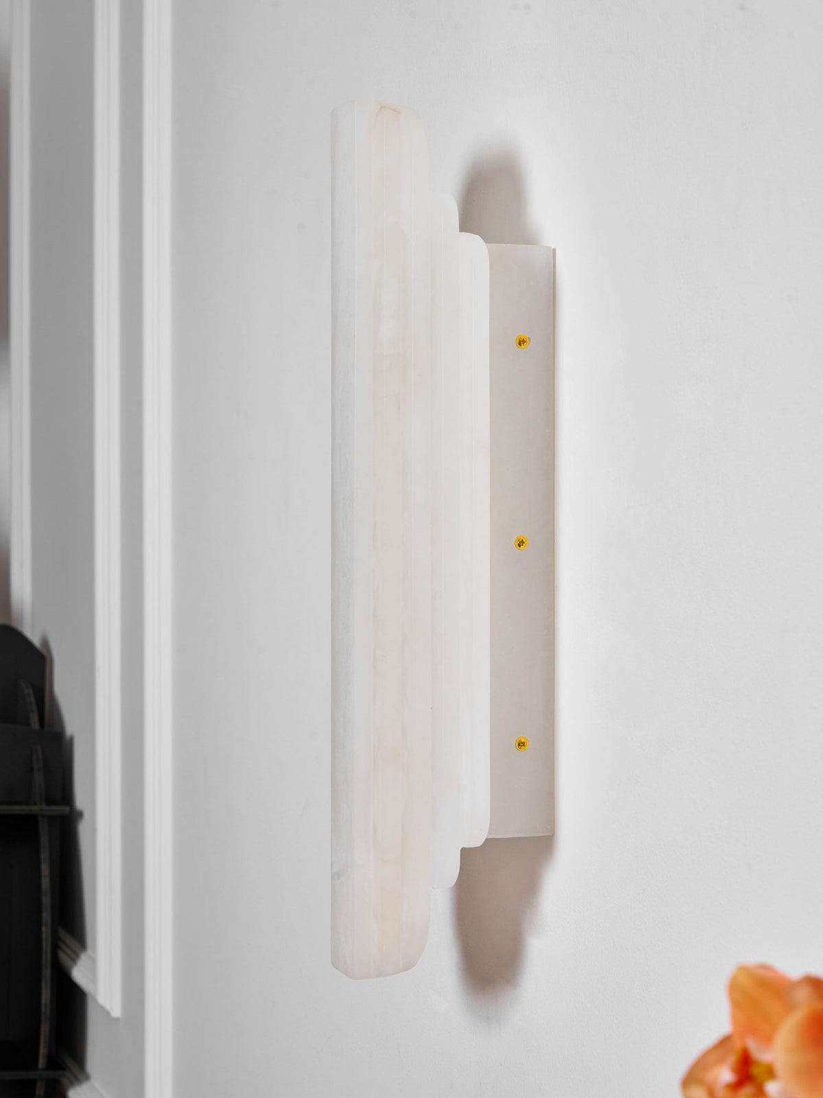 Side view of this unlit Clérachic alabaster sconce on a white wall, showing its pale ribbed shade and the narrow plate with three brass-coloured screws.