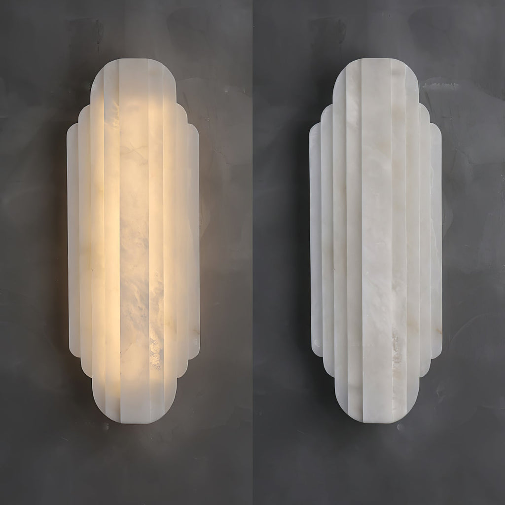 Two views of this Clérachic alabaster sconce on a dark grey wall, one lit and glowing warm, the other unlit and showing its pale stone.