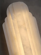 Close view of the top of this Clérachic alabaster sconce, showing its stepped, ribbed shade lit from inside.
