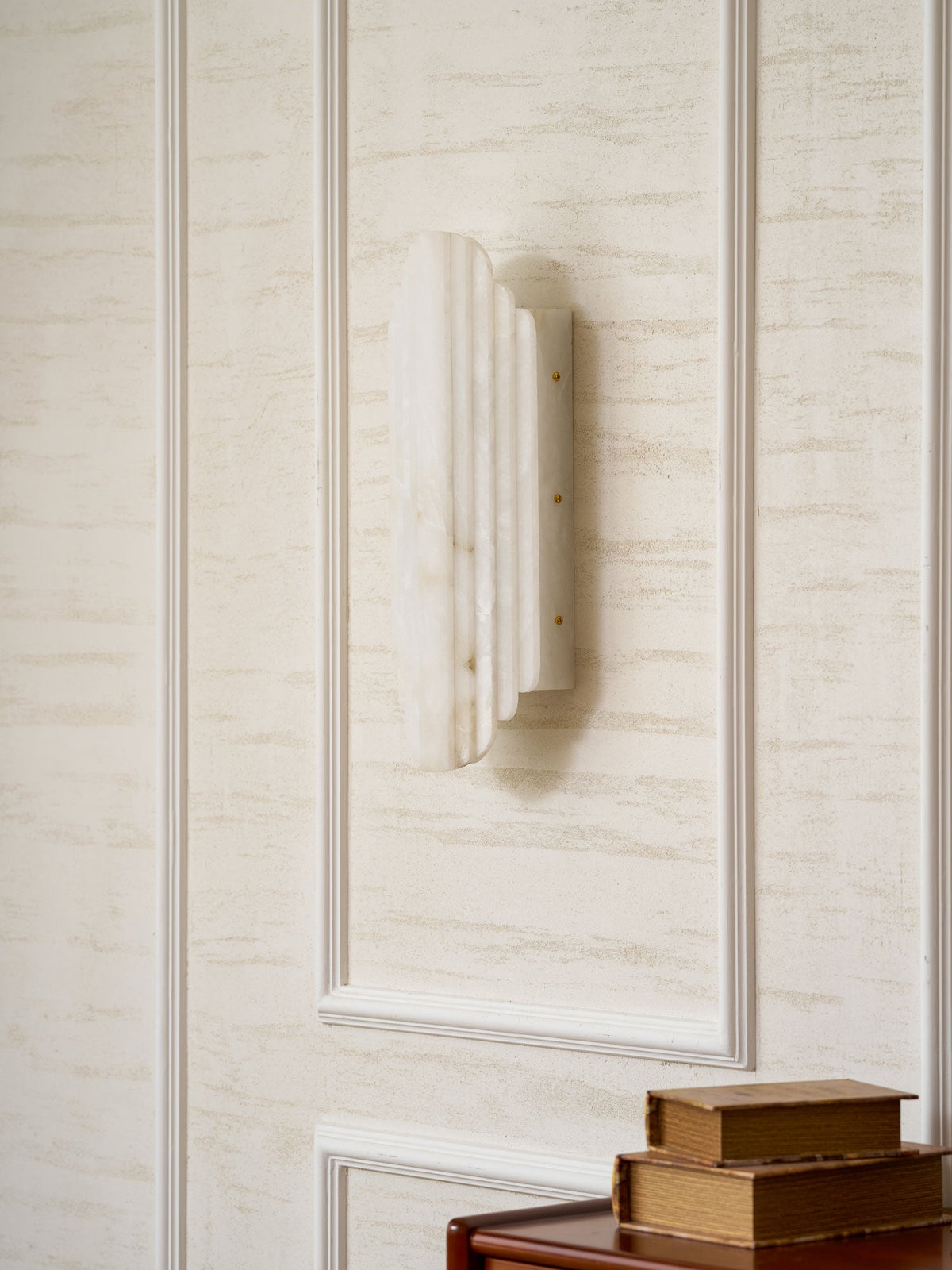 Three-quarter view of the unlit Clérachic alabaster sconce on a panelled wall, showing the ribbed stone and small brass-coloured screws.