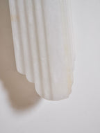 Close view of the lower edge of this Clérachic alabaster sconce, showing the stepped, ribbed stone against a white wall.