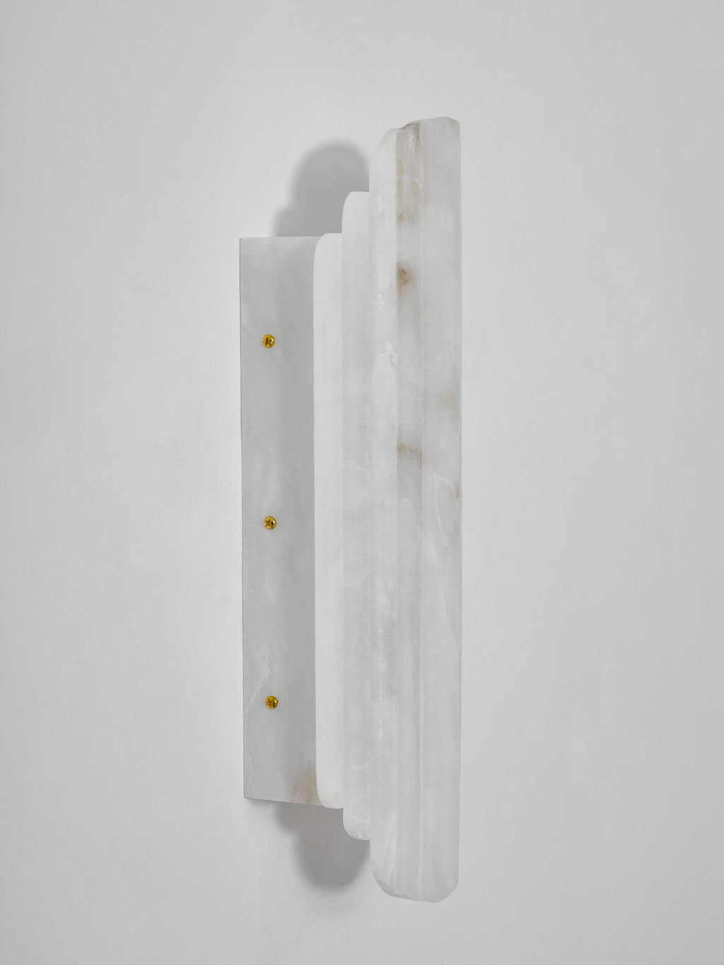 Side view of the unlit Clérachic alabaster sconce, showing its stepped stone panels and the narrow plate fixed with brass-coloured screws.