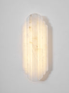 Close front view of the lit Clérachic alabaster sconce, its ribbed shade glowing warm with soft brown veining.
