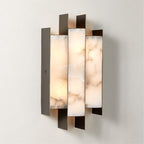 The Clérachic Alabaster Wall Sconce lit on a pale plaster wall, dark metal blades stepping past the glowing stone.