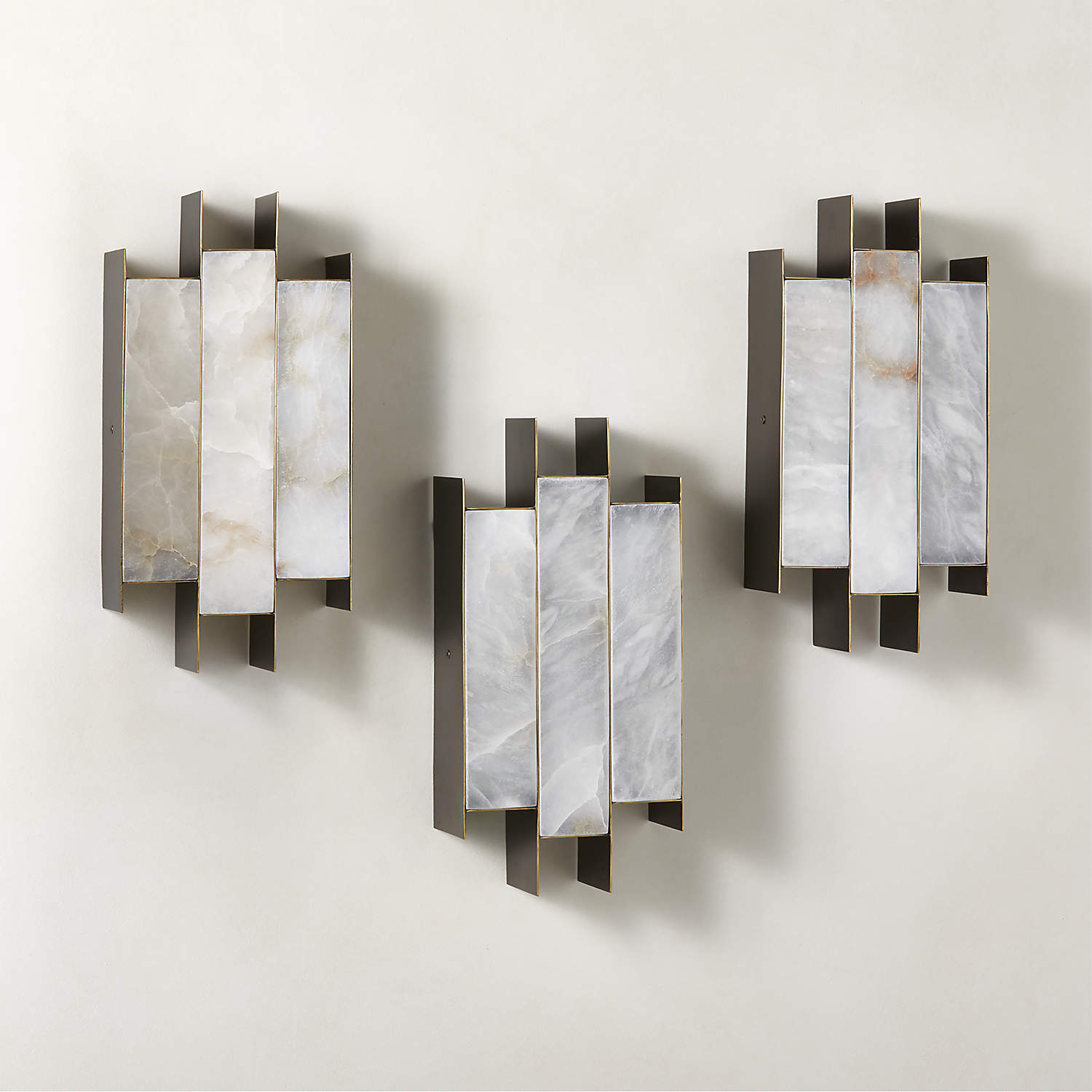 Three Clérachic Alabaster Wall Sconces hung in a staggered group on one wall, each panel carrying its own stone veining.