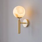 Brushed brass Clérachic alabaster wall sconce with the plain globe shade, the stone's amber veining showing as it glows.
