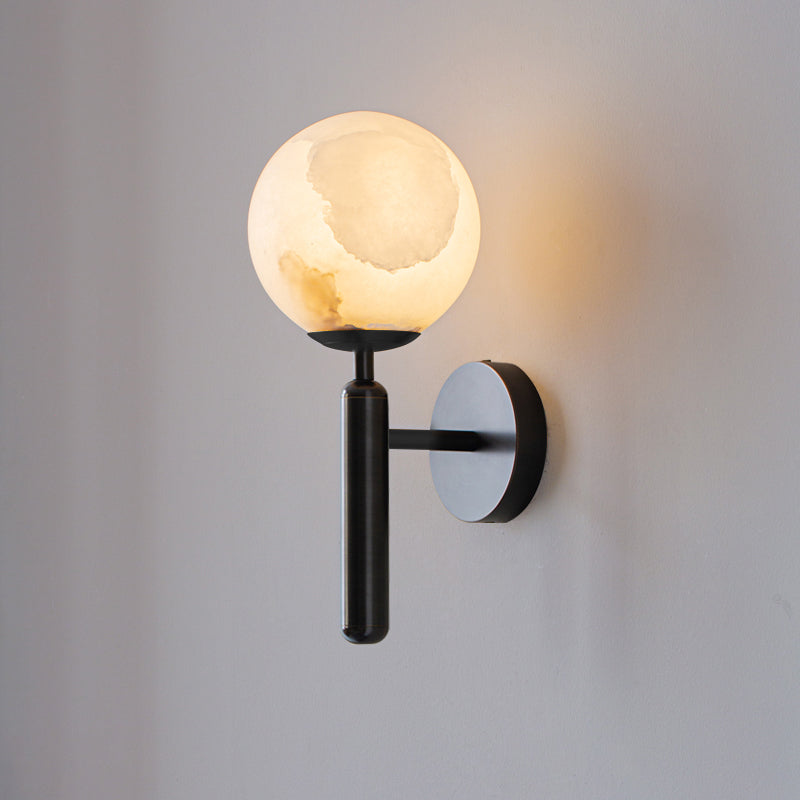 The globe-shade Clérachic alabaster wall sconce in black, arm and baton holding the lit stone away from the wall.