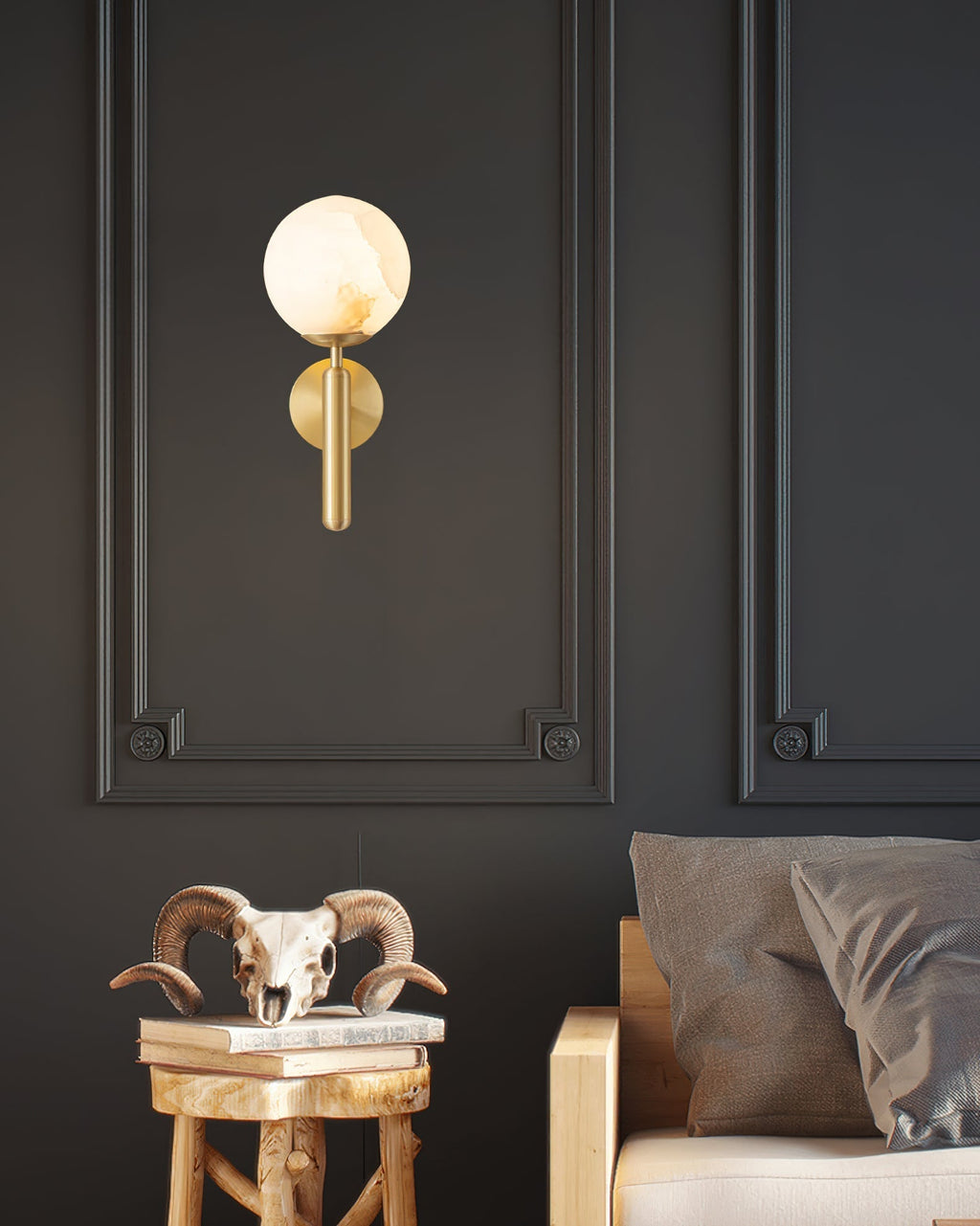 Brass Clérachic alabaster wall sconce with the globe shade glowing against a charcoal panelled wall beside a bed.