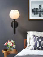 Black-finish Clérachic alabaster wall sconce lit beside a framed print on a charcoal bedroom wall above a made bed.
