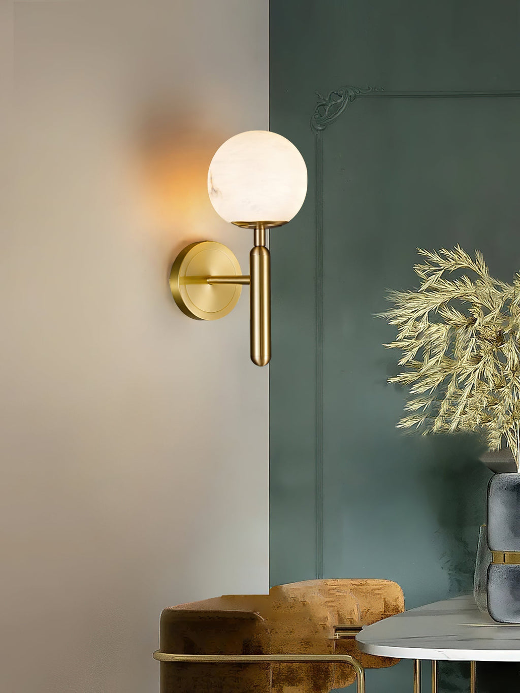 Clérachic alabaster wall sconce in brass on a corner wall, globe shade lit beside a deep green panel and gold dried stems.