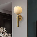 Close three-quarter view of the brass Clérachic alabaster wall sconce, its scalloped stone rim glowing on a corner wall.