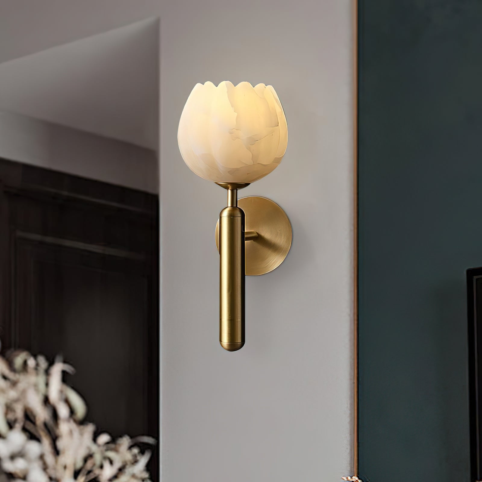 Close three-quarter view of the brass Clérachic alabaster wall sconce, its scalloped stone rim glowing on a corner wall.